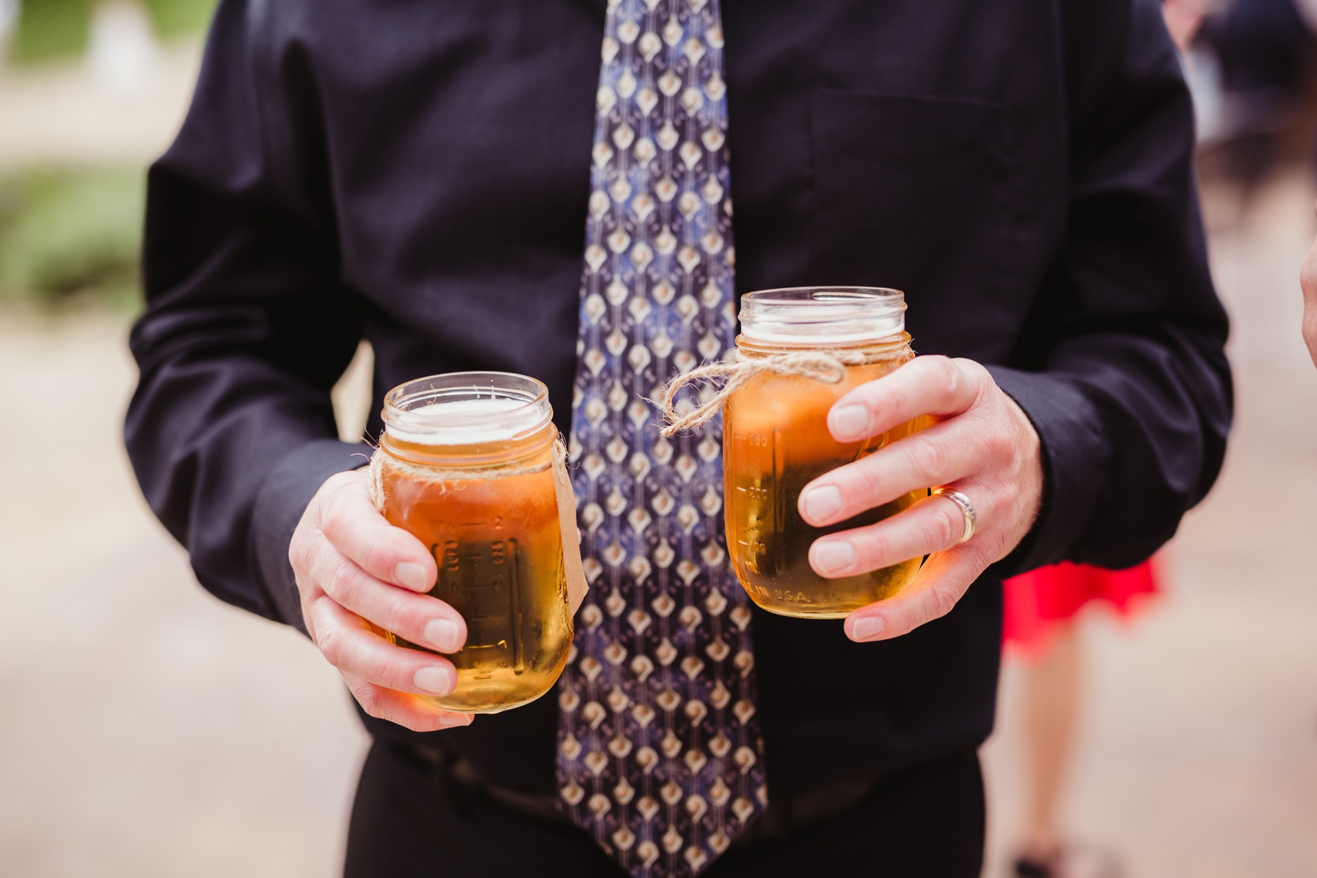 Man holding glass jars of beer at outdoor party